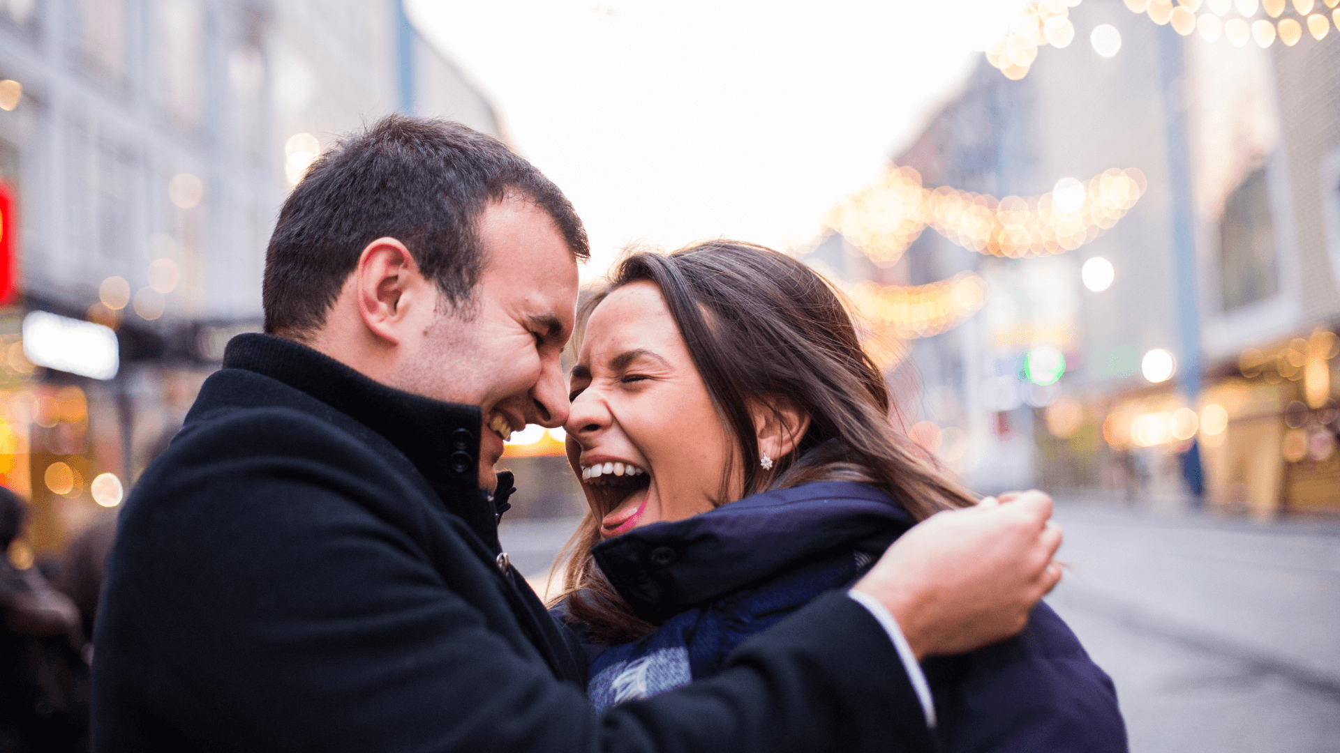 Couple facing each other and laughing hard in the middle of the street